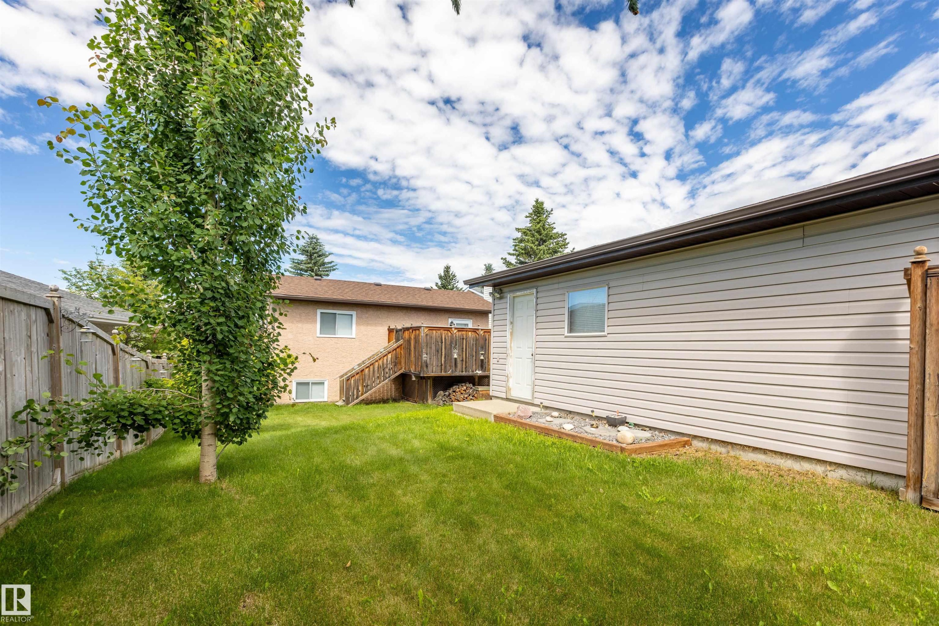 Expansive grassy lawn bordered by a wood fence and mature trees - 3 Glenforest Crescent, Stony Plain, AB