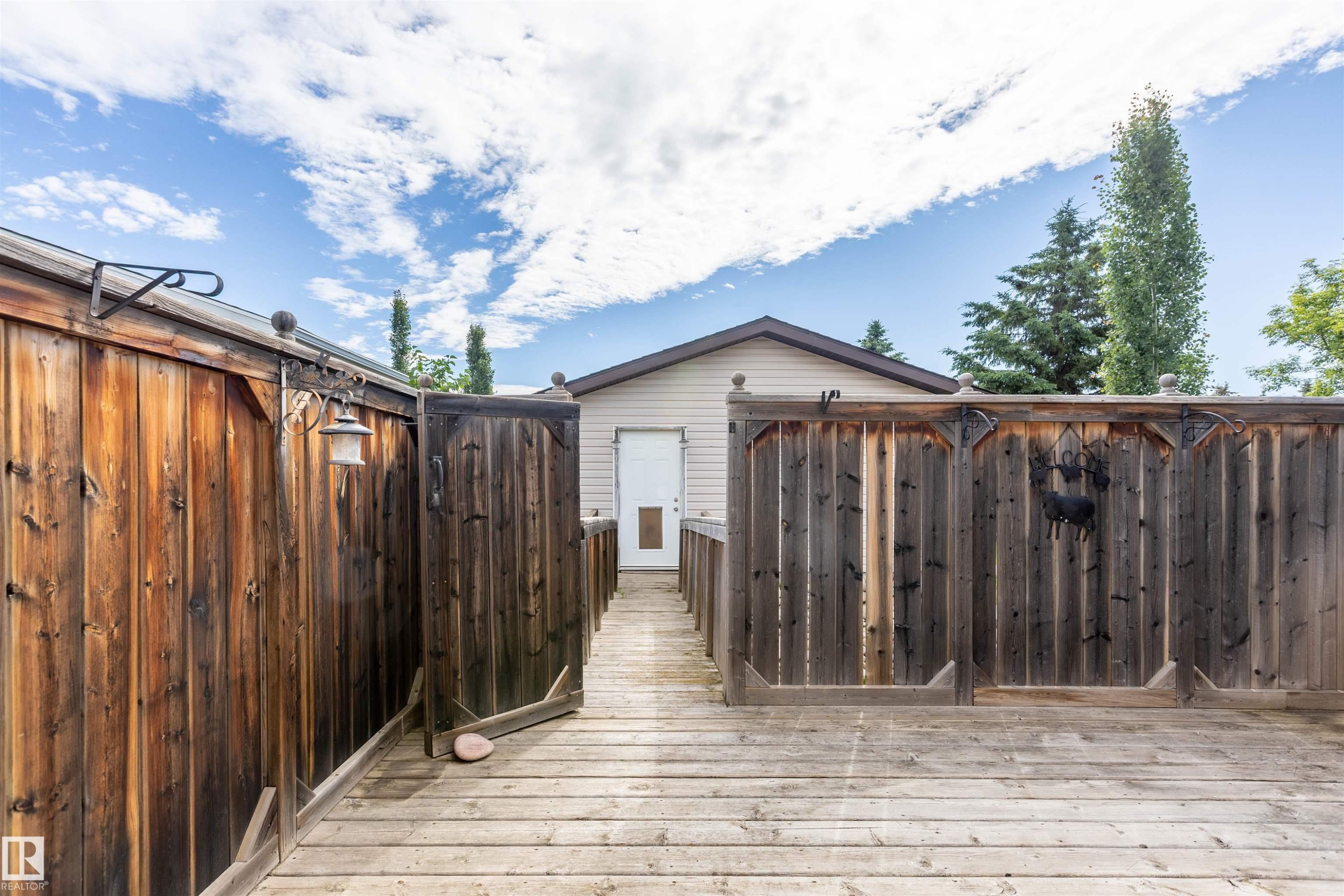 Expansive outdoor decking features a wood-paneled privacy fence and a built-in outdoor light fixture - 3 Glenforest Crescent, Stony Plain, AB