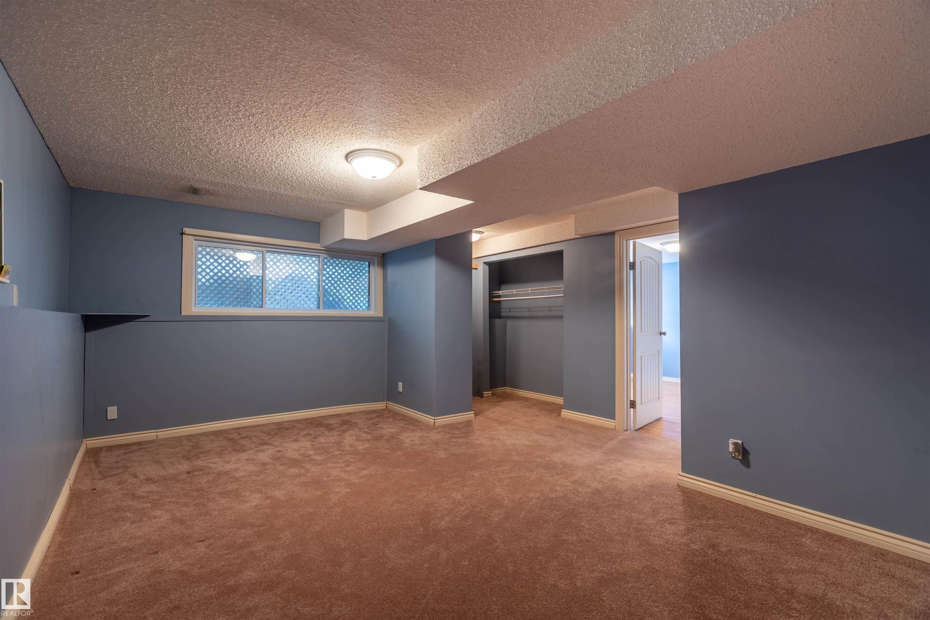 Carpeted room featuring a window with a patterned privacy screen, a built-in closet with shelving, and recessed lighting - 3 Glenforest Crescent, Stony Plain, AB