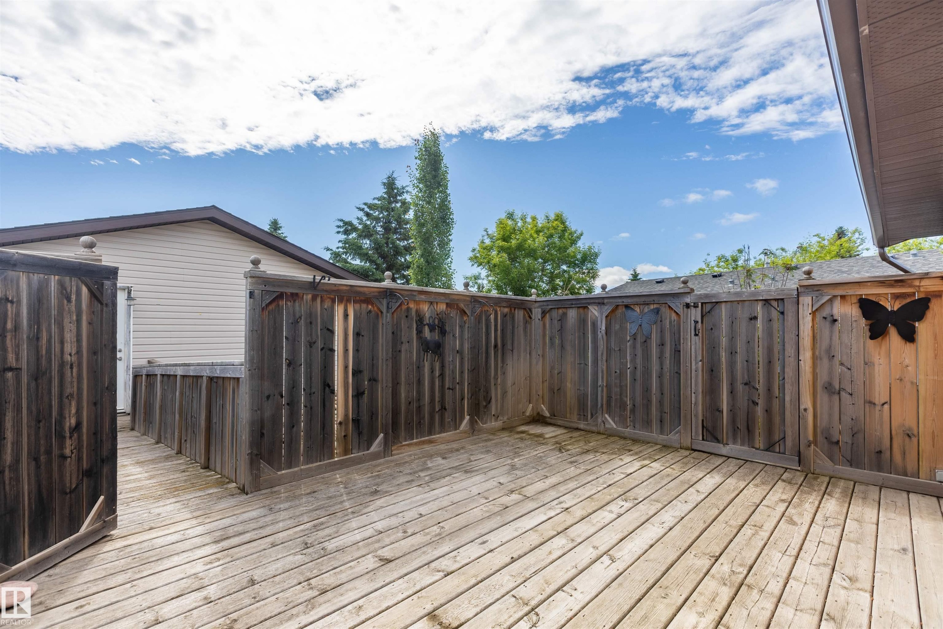 Spacious wood-finish deck area featuring privacy fencing and a dedicated access point to the structure - 3 Glenforest Crescent, Stony Plain, AB