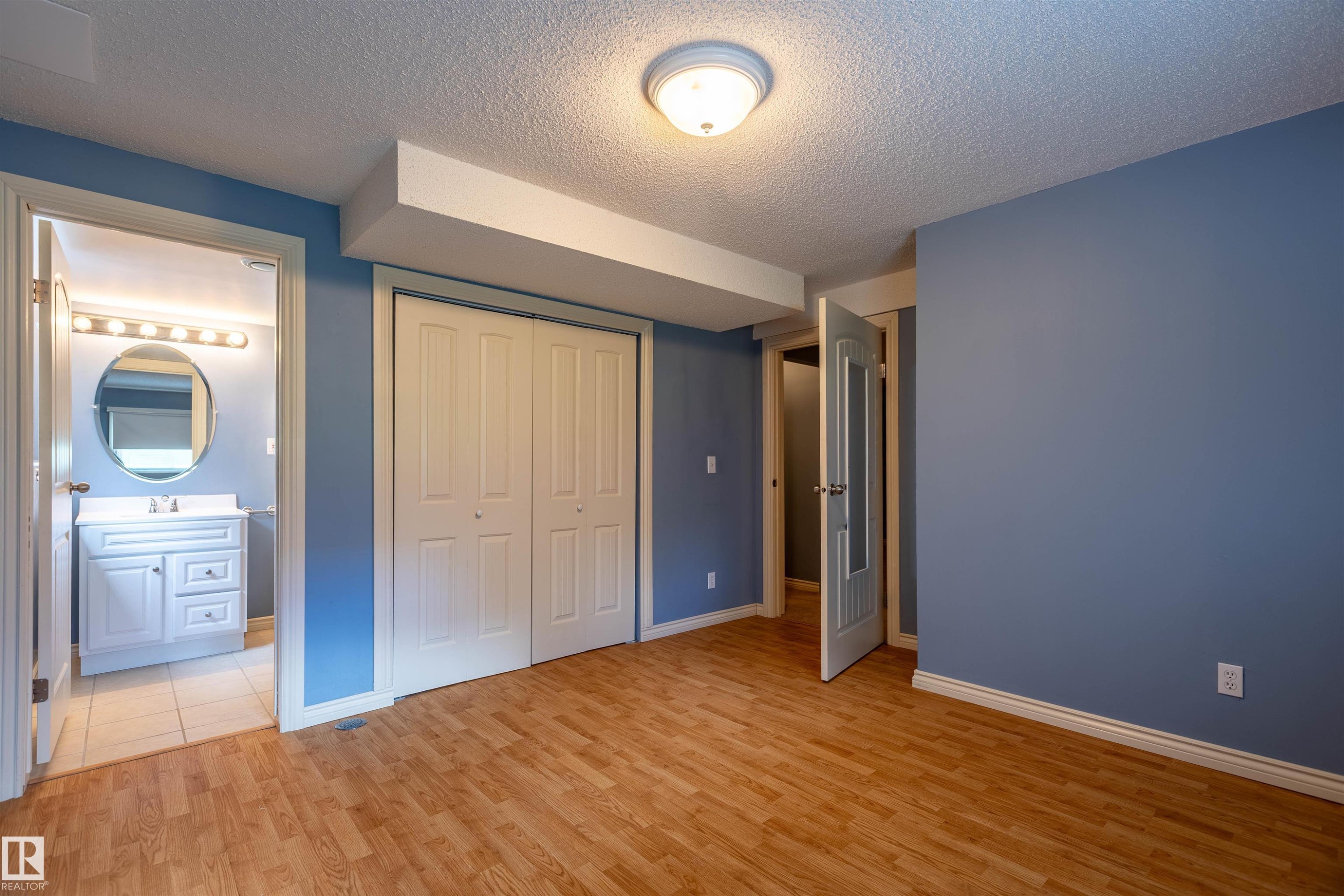 Room featuring wood-finish flooring, light blue walls, and a white bi-fold closet - 3 Glenforest Crescent, Stony Plain, AB