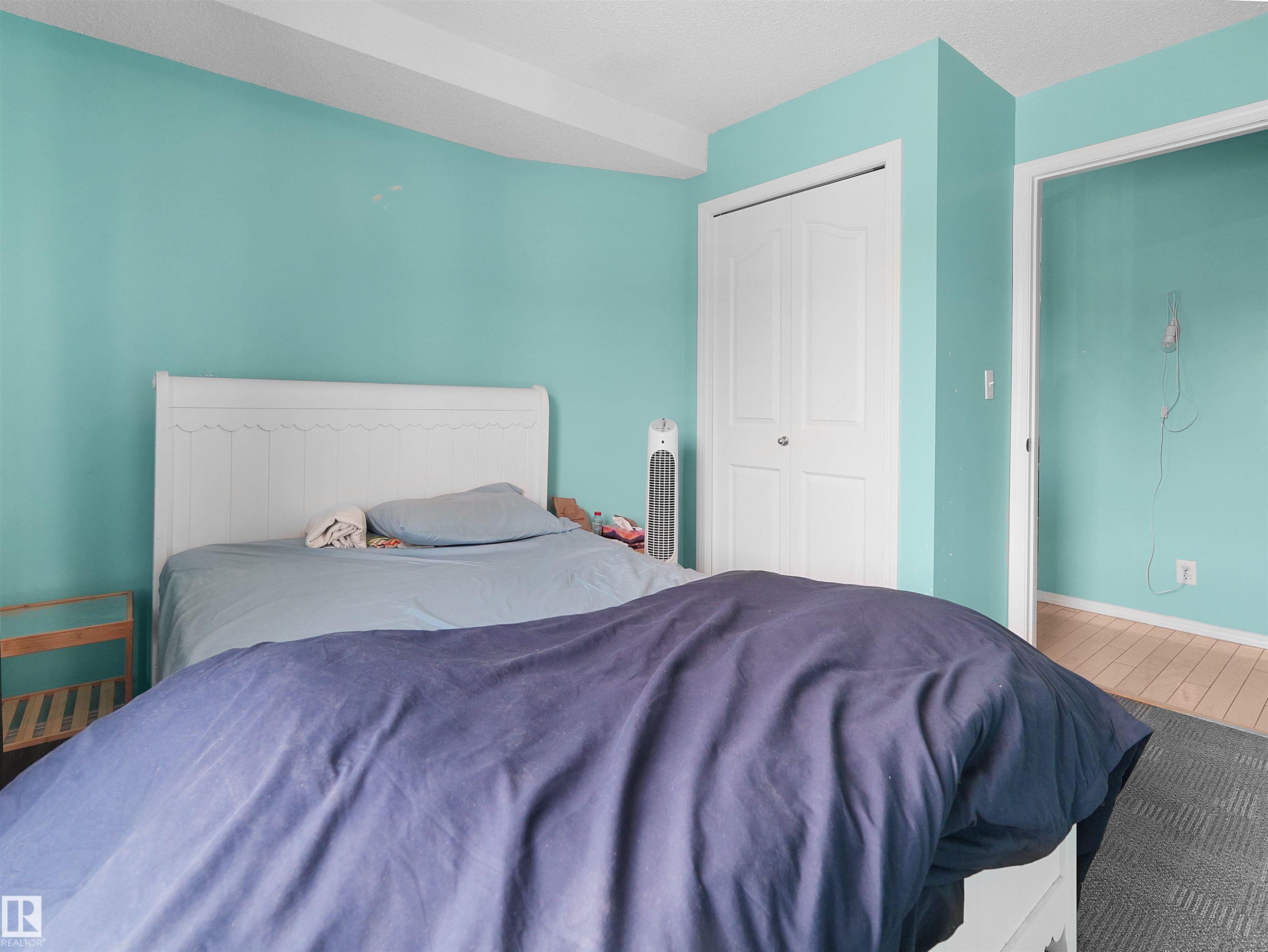 Bedroom featuring a white headboard, white bi-fold closet doors, and wall-to-wall carpeting - #313 11820 22 Av Sw, Edmonton, AB - Indoor Photo Showing Bedroom