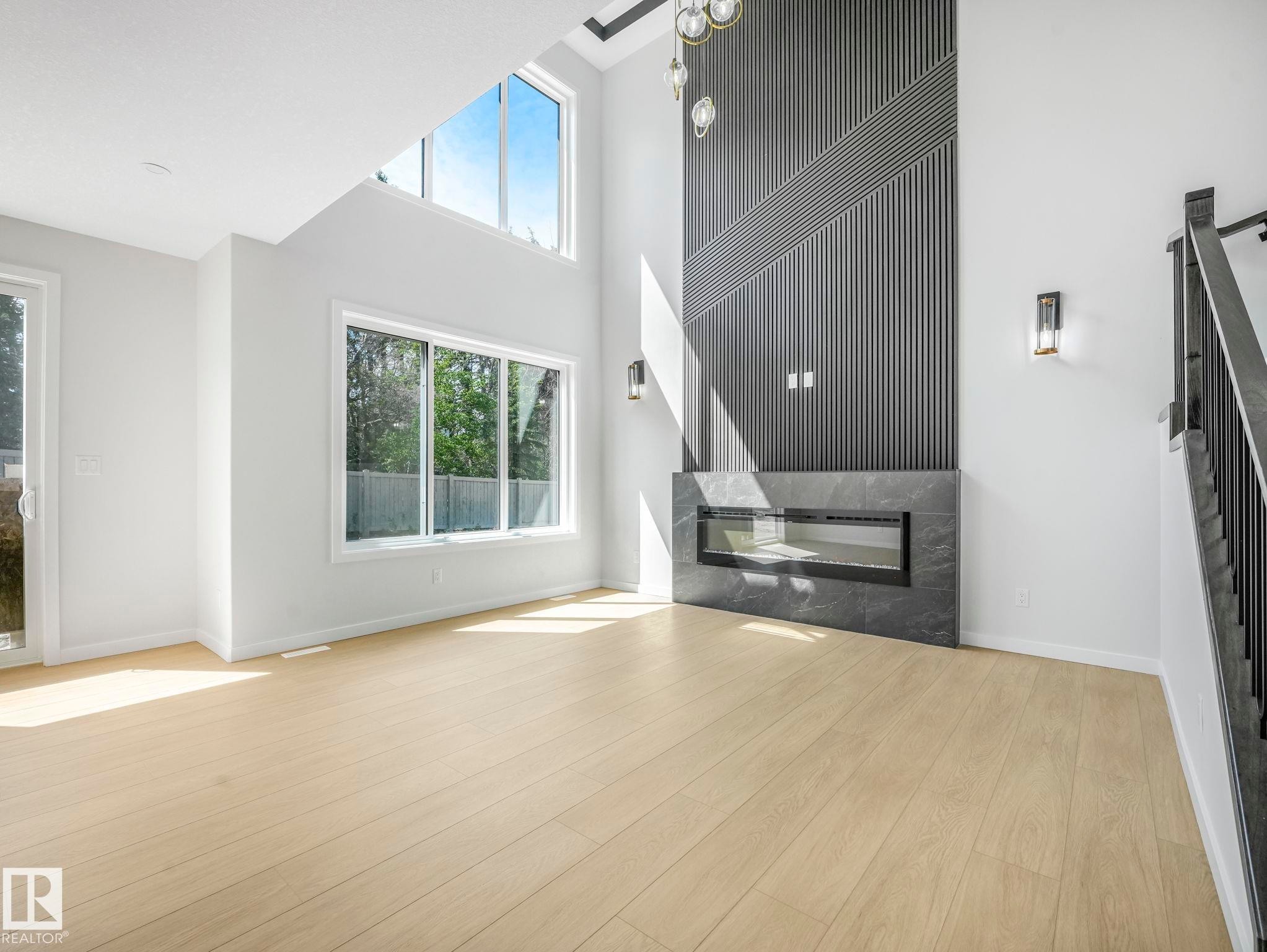 Spacious room featuring a contemporary linear fireplace with a dark stone-finish surround - 1717 Crossbill Loop, Edmonton, AB - Indoor With Fireplace