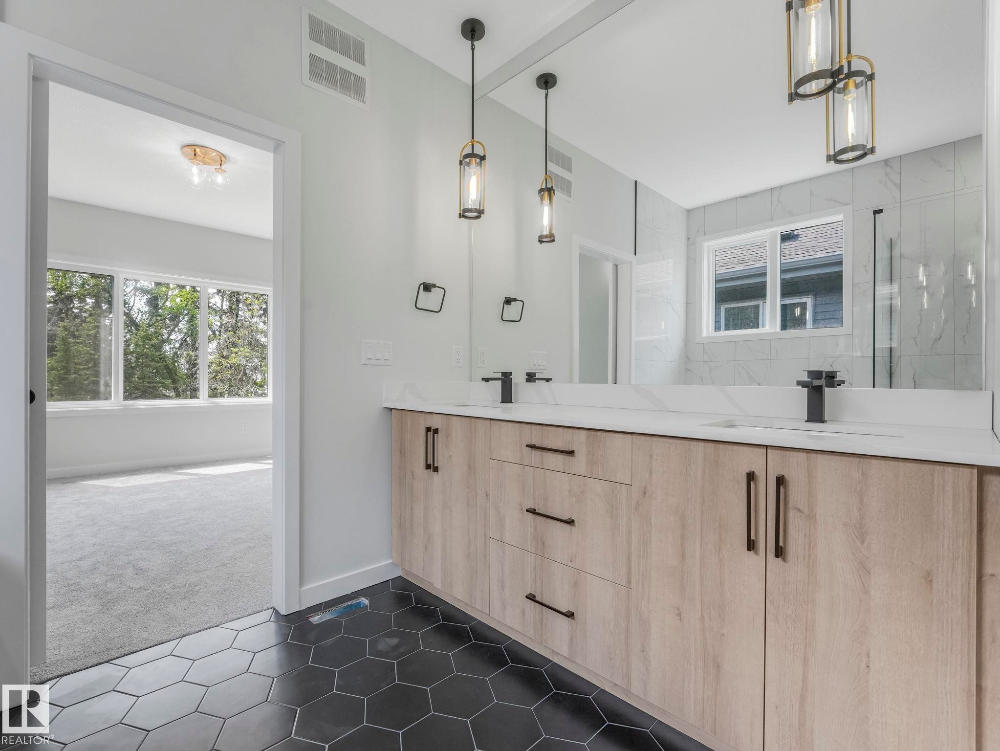 Modern bathroom vanity featuring dual sinks, matte black fixtures, quartz countertops, and a full-width mirror - 1717 Crossbill Loop, Edmonton, AB - Indoor Photo Showing Bathroom