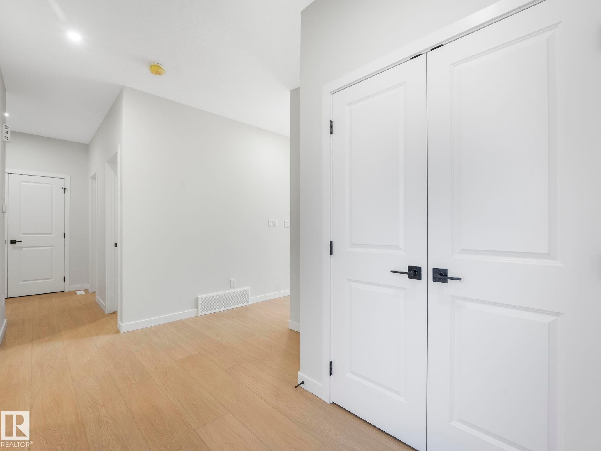 Hallway featuring light wood-finish flooring, white walls, and bright overhead lighting - 1717 Crossbill Loop, Edmonton, AB - Indoor Photo Showing Other Room
