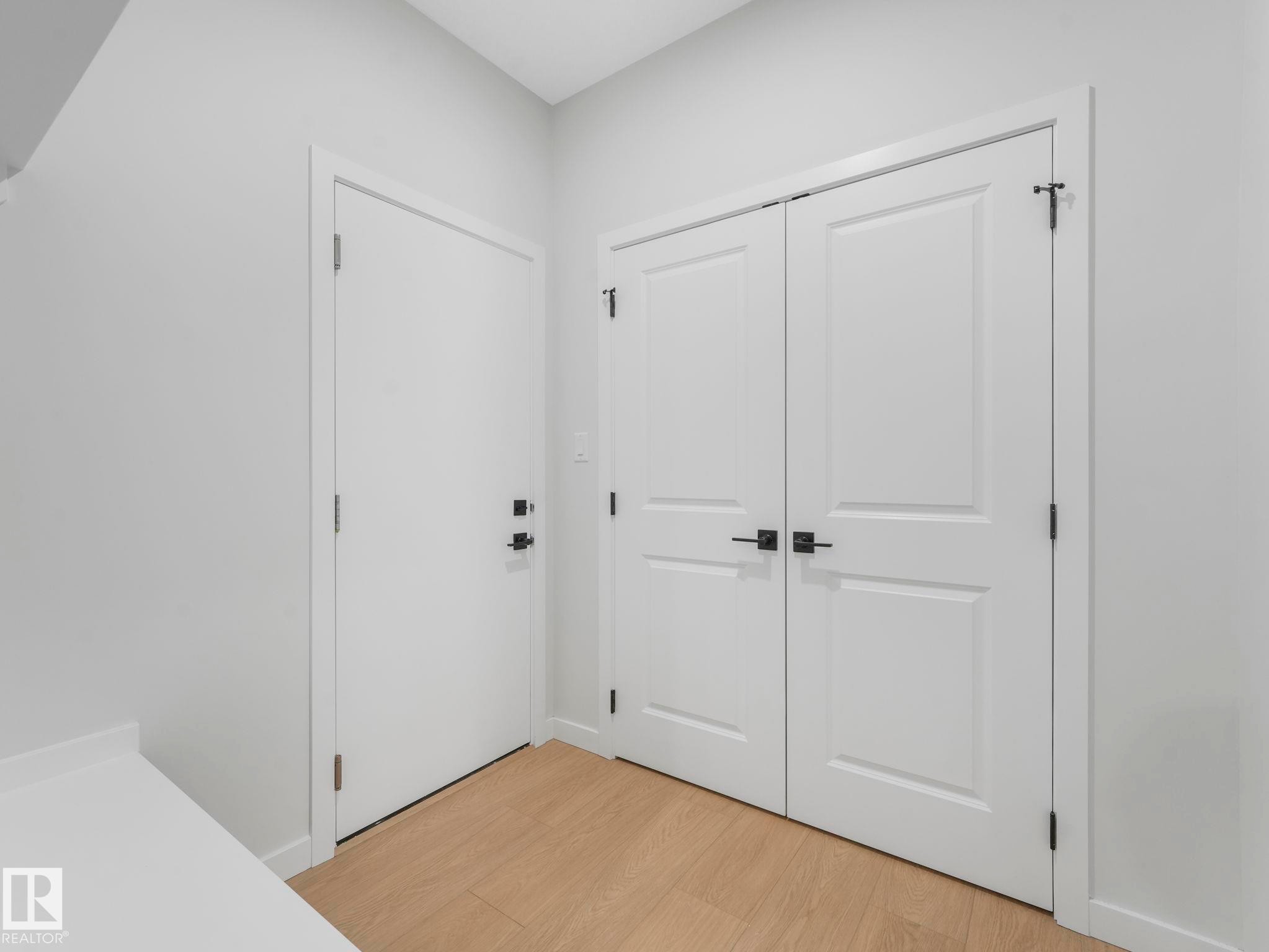 Entryway featuring wood-finish flooring, a white solid door with black hardware, and a double-door closet with black hardware - 1717 Crossbill Loop, Edmonton, AB - Indoor Photo Showing Other Room
