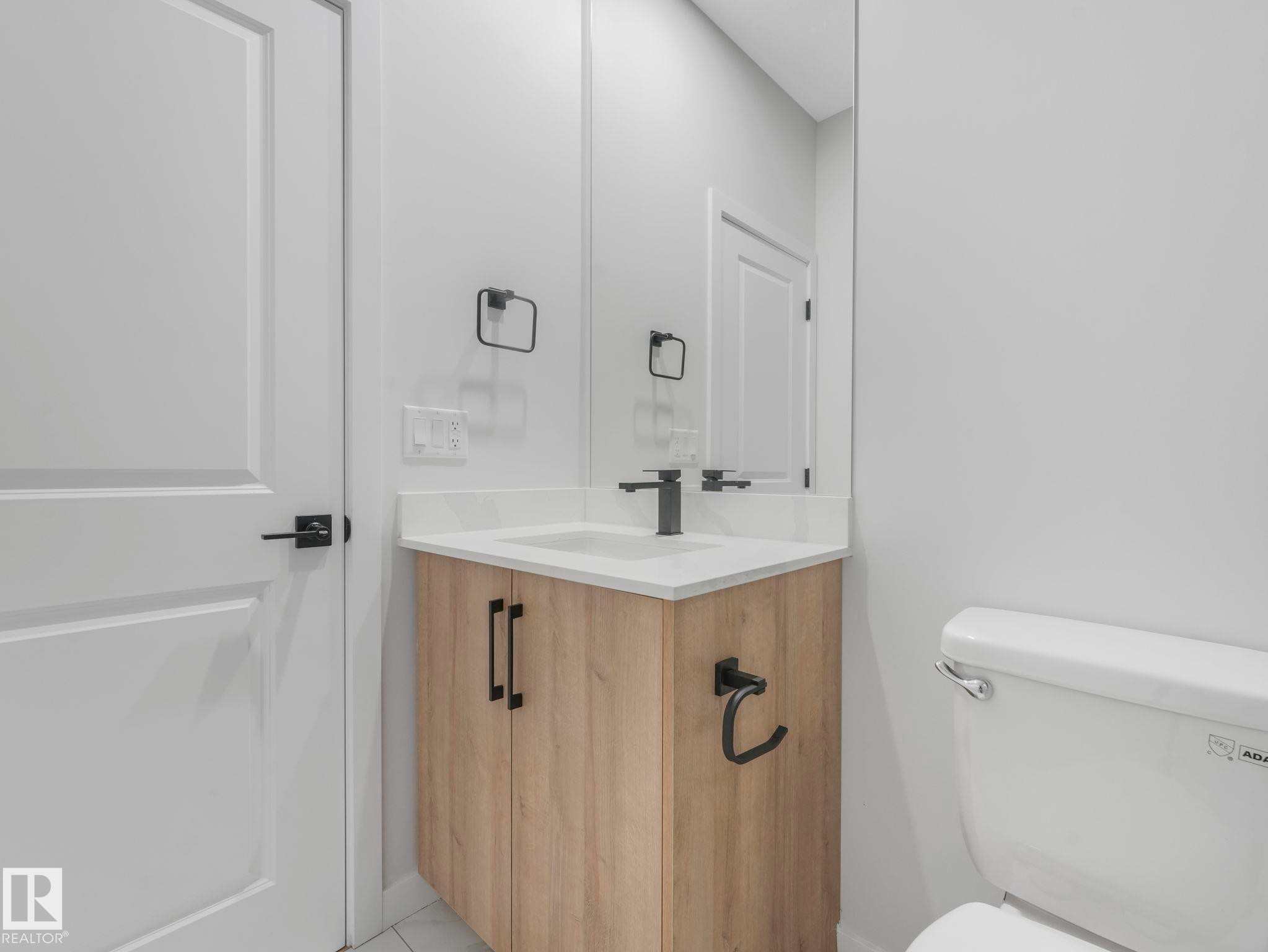 Modern bathroom vanity with wood-finish cabinetry and matte black hardware - 1717 Crossbill Loop, Edmonton, AB - Indoor Photo Showing Bathroom