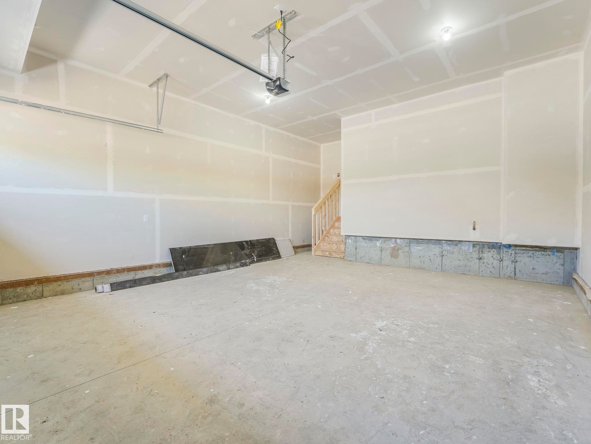 Spacious garage featuring a concrete floor, unpainted drywall, exposed overhead garage door mechanism, and recessed lighting - 1717 Crossbill Loop, Edmonton, AB - Indoor Photo Showing Garage