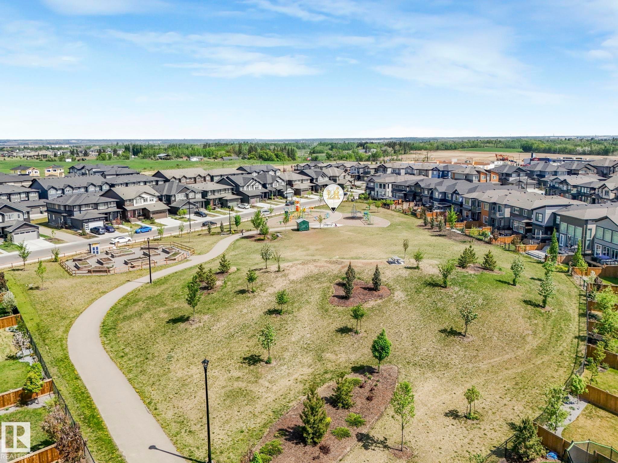 Expansive greenspace featuring a paved walking path, scattered trees, and a central play area - 1717 Crossbill Loop, Edmonton, AB - Outdoor With View