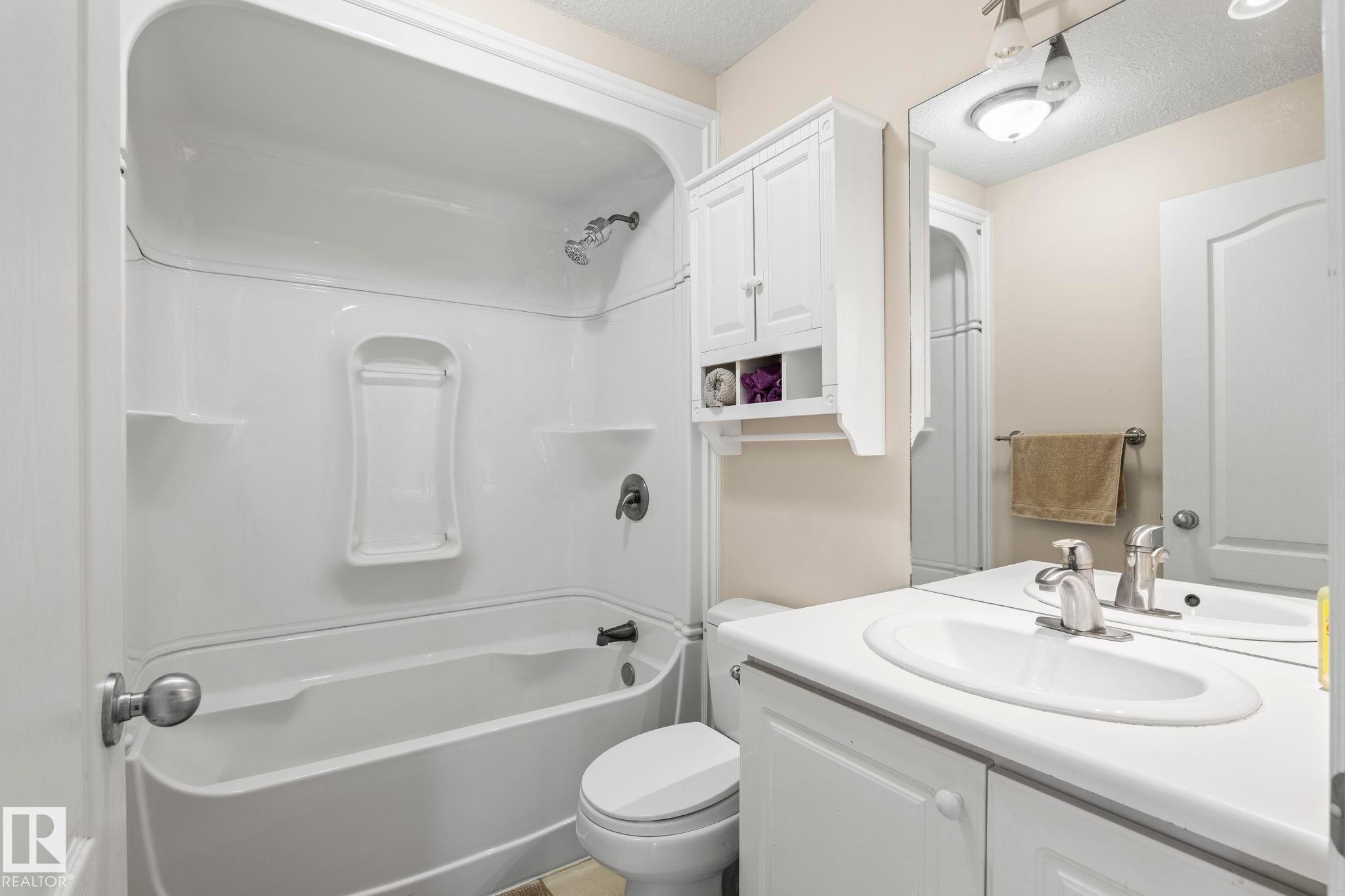 Bathroom featuring a white bathtub and shower surround with integrated shelving - 860 41 Avenue, Edmonton, AB