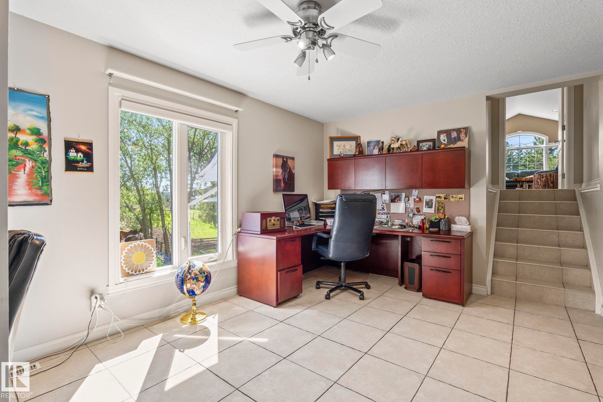 Spacious room featuring light-toned tile flooring, a large window offering exterior views, and a ceiling fan with integrated lighting - 860 41 Avenue, Edmonton, AB