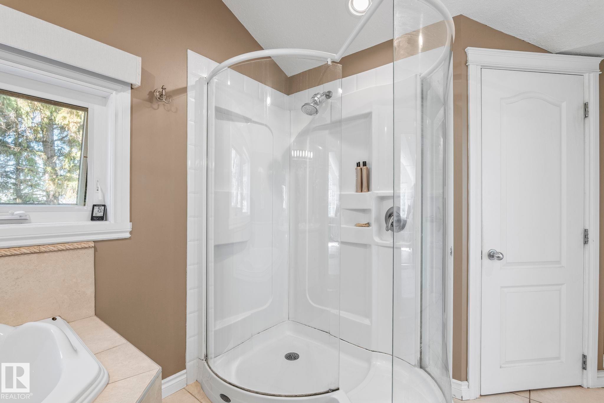 Corner shower enclosure featuring clear glass panels and an integrated shower head - 860 41 Avenue, Edmonton, AB