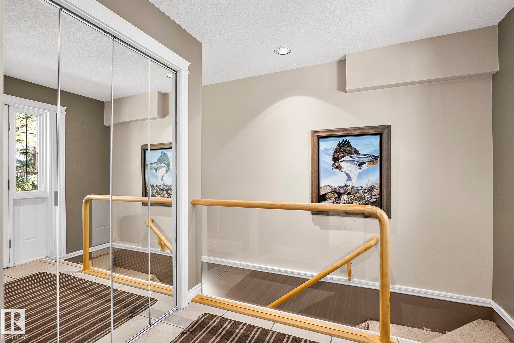 Mirrored closet doors providing visual expansion, alongside a glass panel and wood handrail staircase - 860 41 Avenue, Edmonton, AB