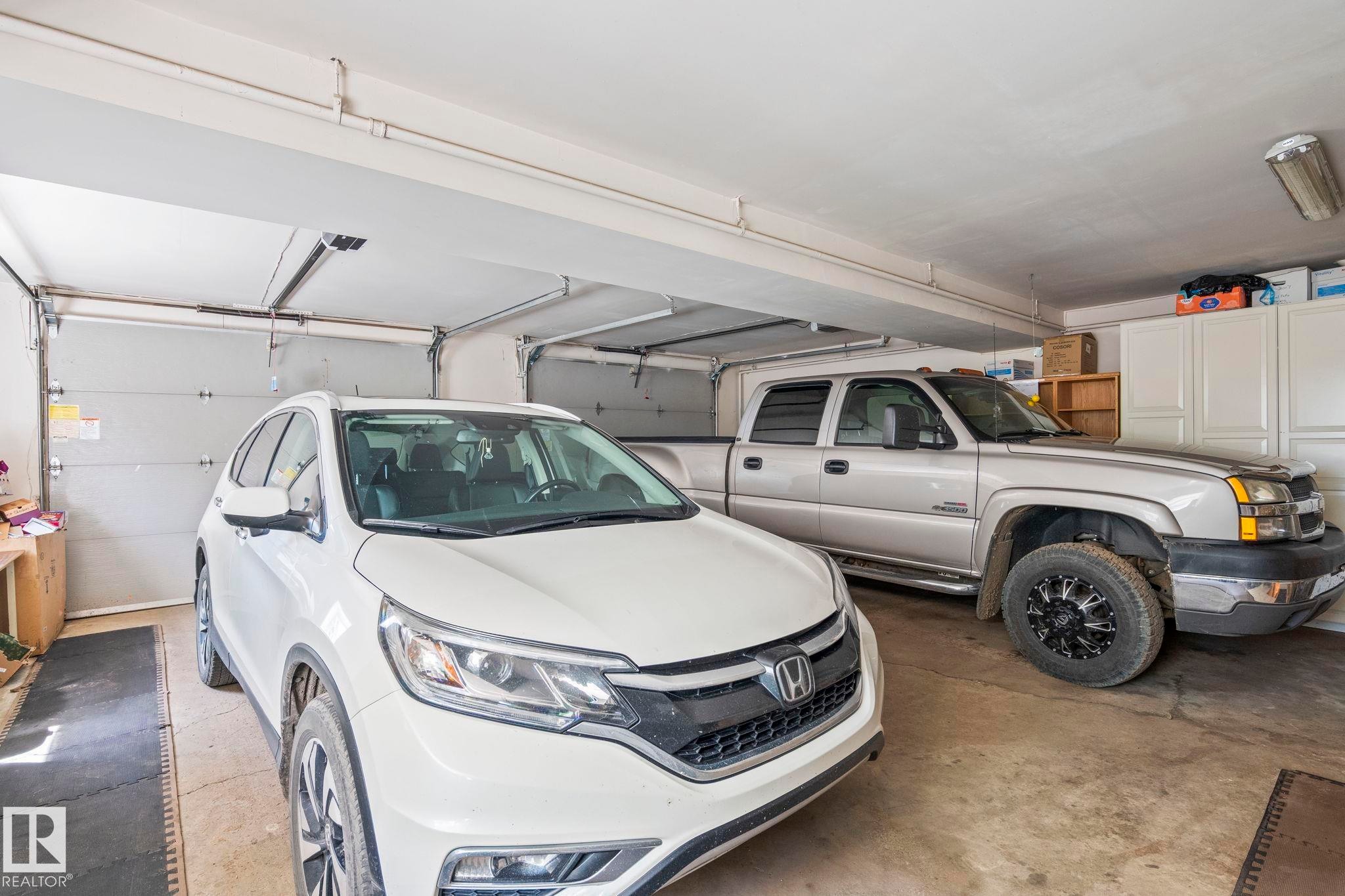 Spacious two-car garage featuring two overhead garage doors, concrete flooring, and built-in storage cabinetry - 860 41 Avenue, Edmonton, AB