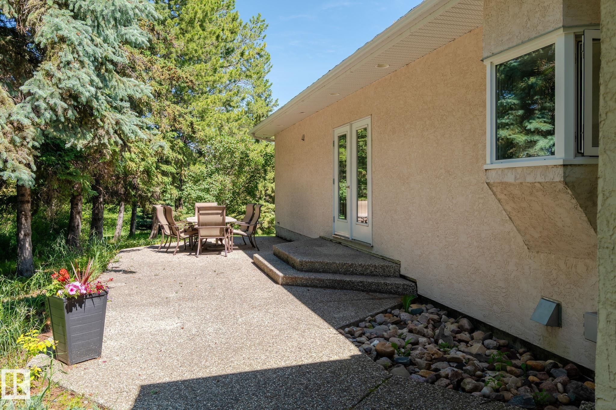 Stucco exterior featuring a bay window, concrete patio, and direct access via French doors - 860 41 Avenue, Edmonton, AB