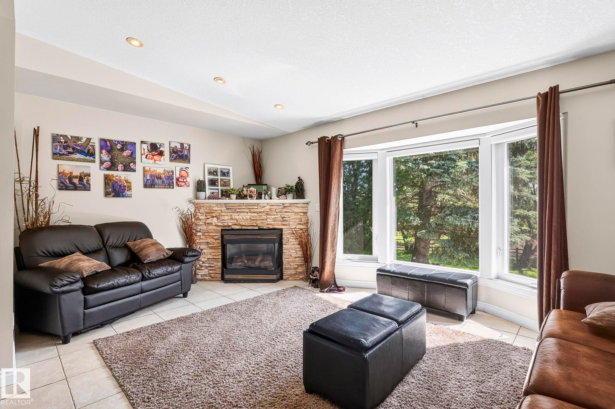Spacious living area featuring a bay window, recessed lighting, and a stone-clad fireplace with a hearth - 860 41 Avenue, Edmonton, AB