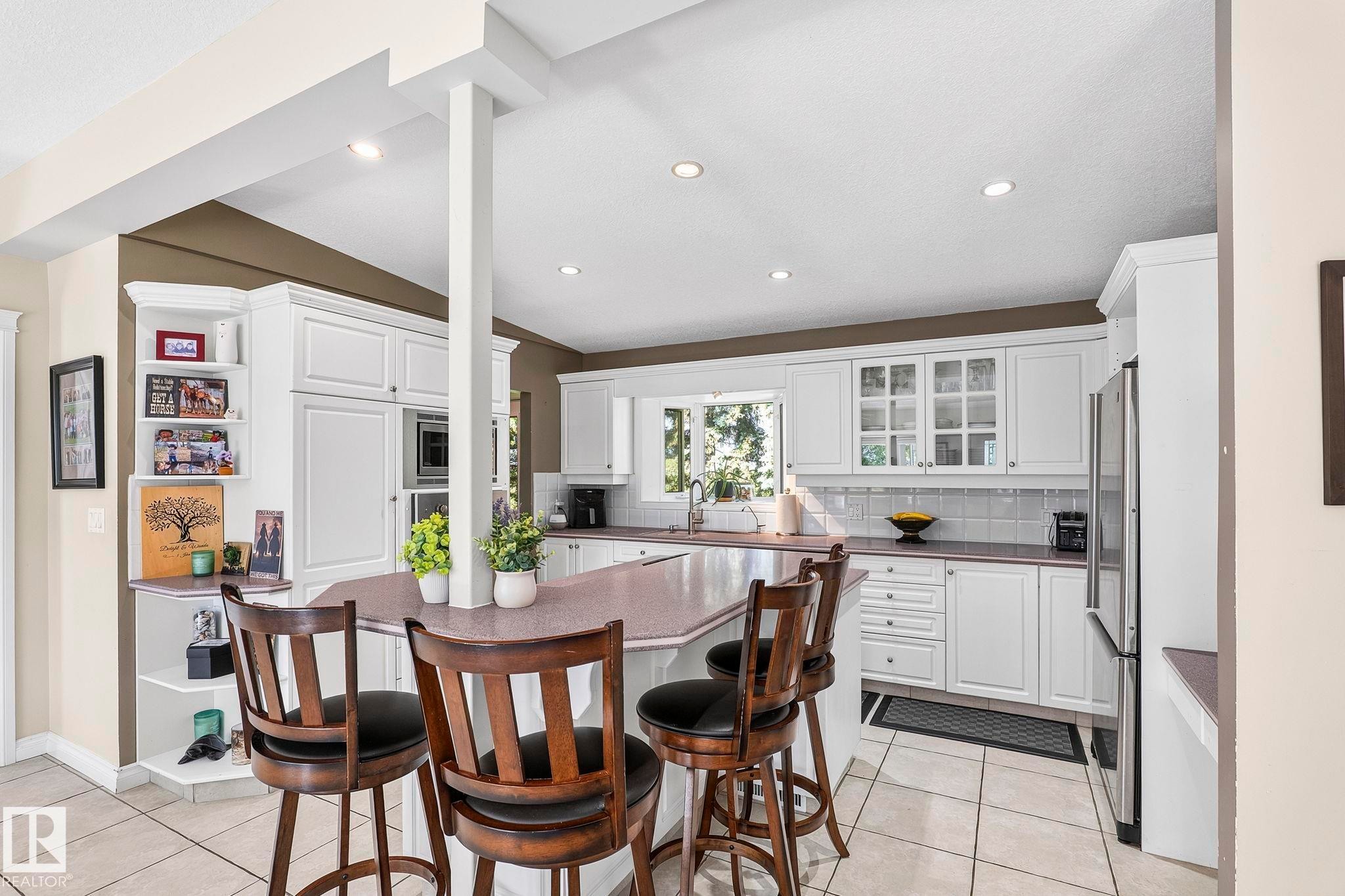 Kitchen featuring a central island with seating for four, white cabinetry, integrated appliances, recessed lighting, and tile flooring - 860 41 Avenue, Edmonton, AB
