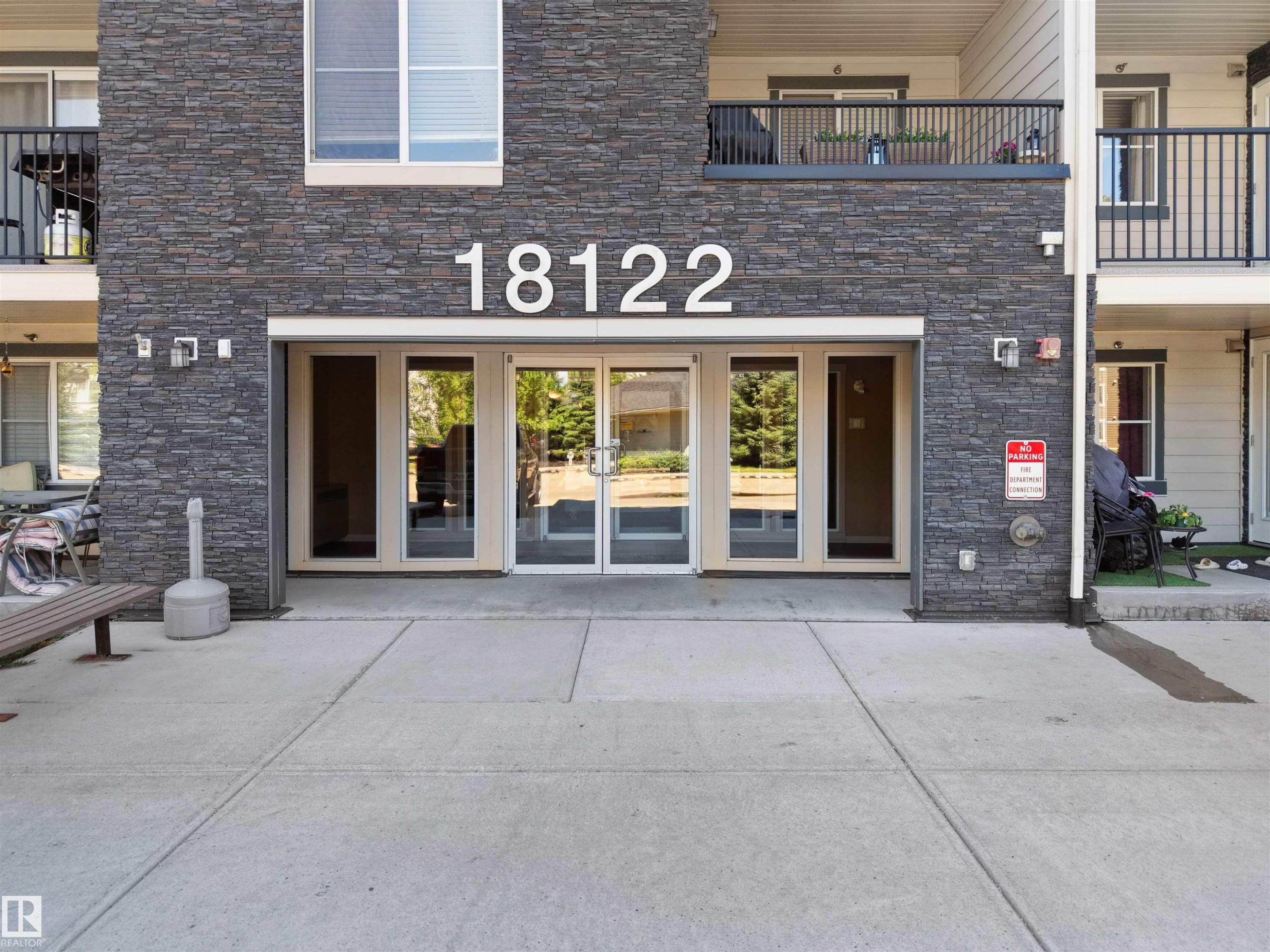 Modern multi-level building with stacked stone facade and concrete walkways - 410 18122 77 Street, Edmonton, AB