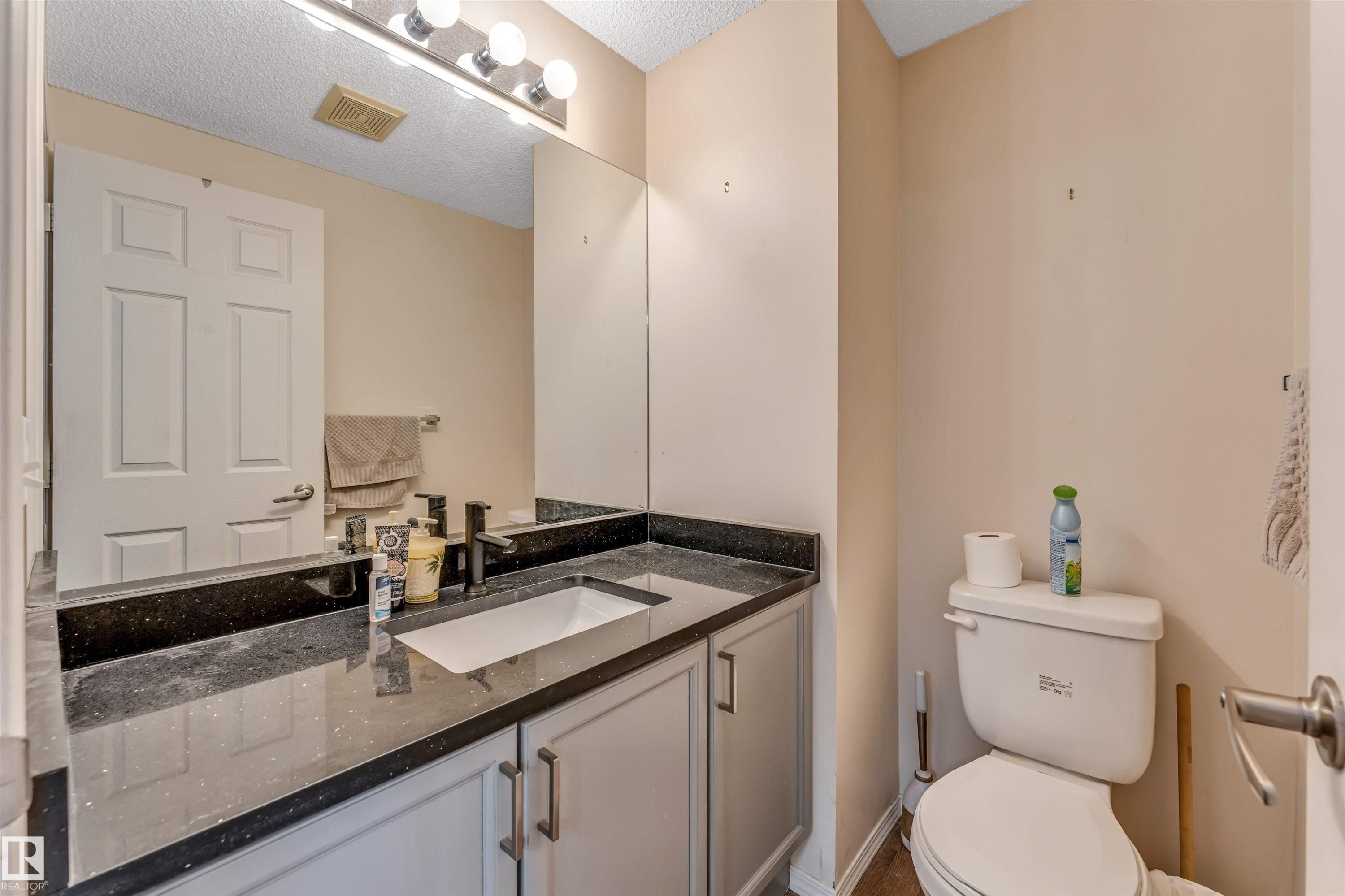 Bathroom vanity featuring a dark speckled countertop with an integrated rectangular sink - 3032 31 Avenue, Edmonton, AB - Indoor Photo Showing Bathroom