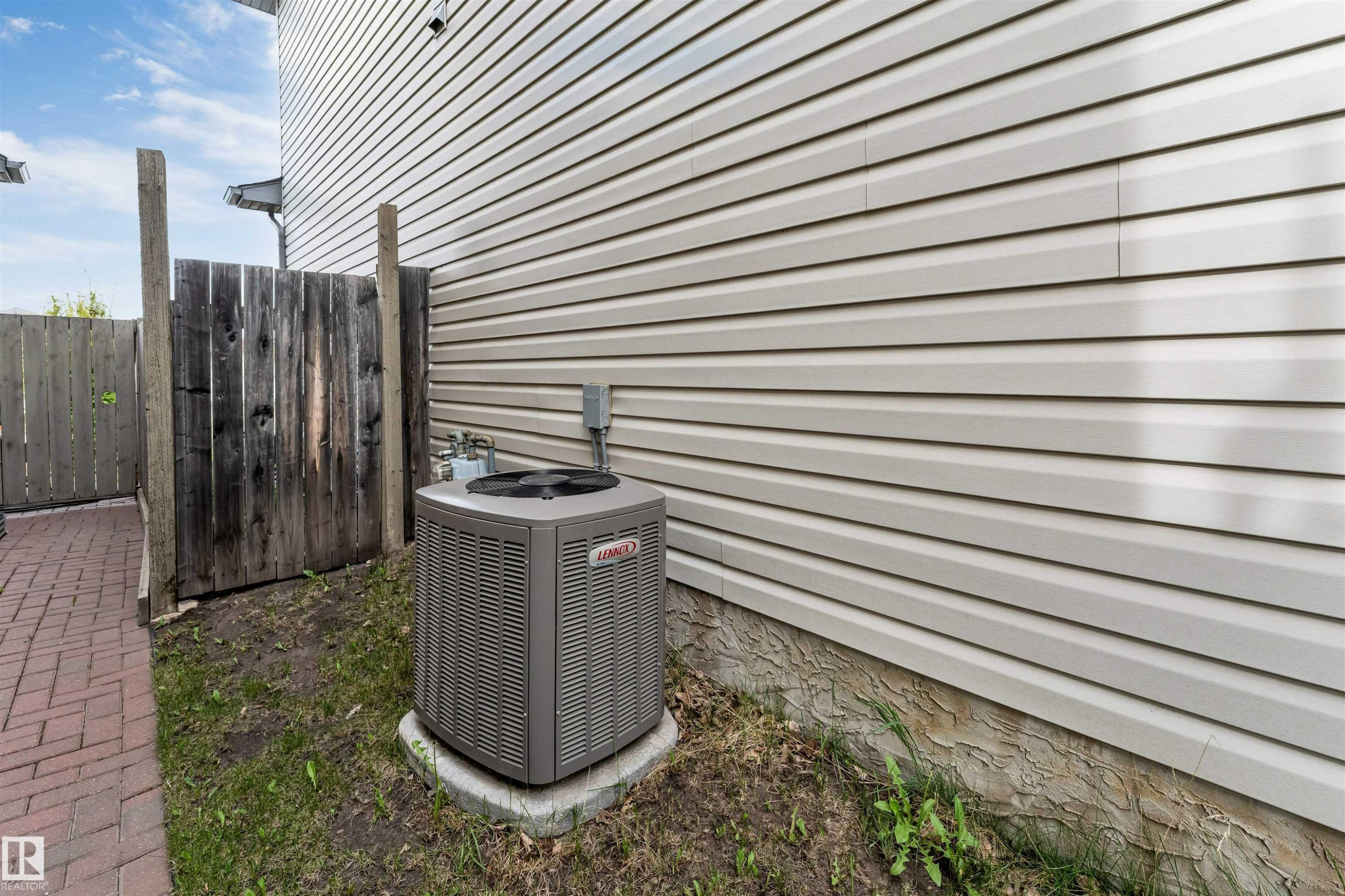 Exterior wall with horizontal siding, featuring a Lennox air conditioning unit on a concrete pad - 3032 31 Avenue, Edmonton, AB - Outdoor