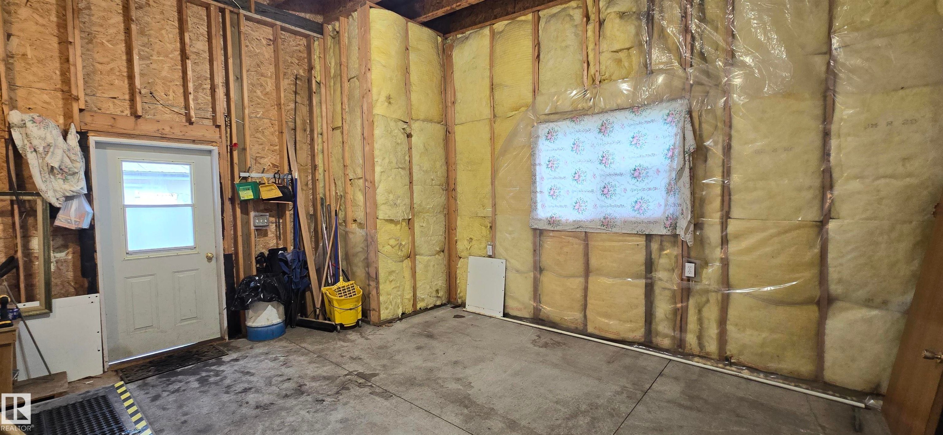 Framed interior space featuring insulated walls, a concrete floor, and a white entry door - 5304 49 Street, Two Hills, AB - Indoor Photo Showing Basement