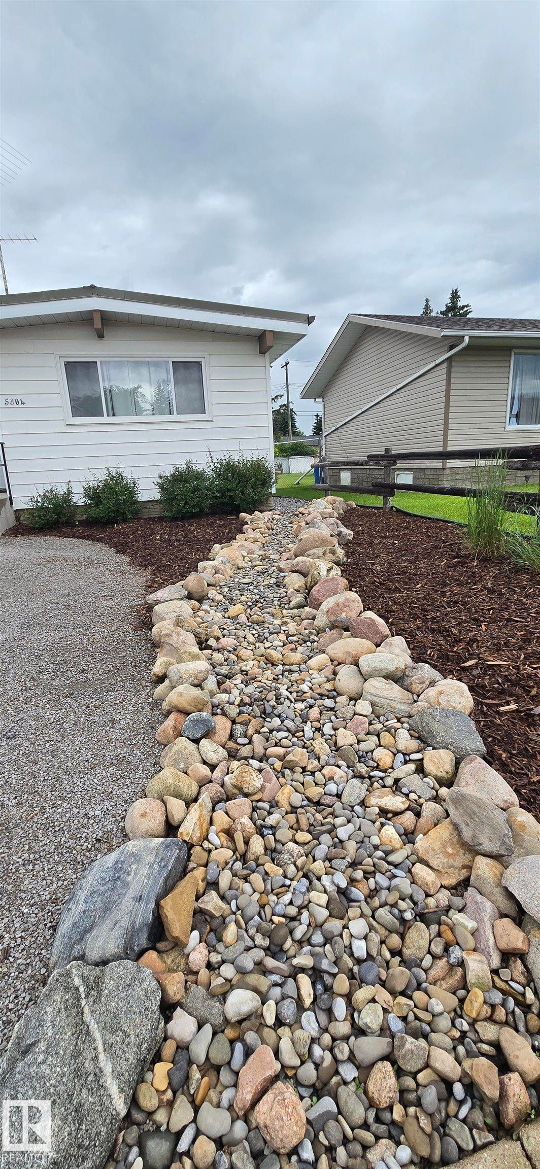 Rock-lined dry creek bed featuring natural stone and various sized pebbles - 5304 49 Street, Two Hills, AB - Outdoor