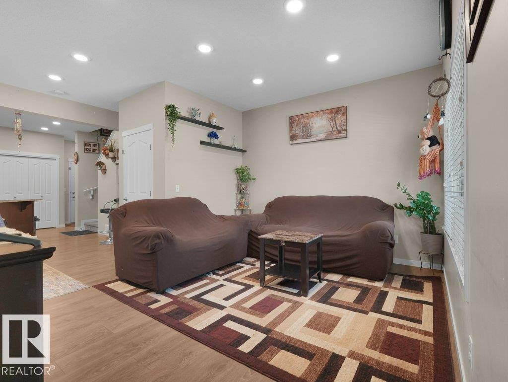 Recessed lighting illuminates this living area featuring wood-finish flooring and light-toned wall paint - 1419 27 Av, Edmonton, AB
