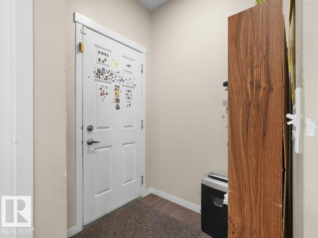 White paneled door with brushed nickel hardware, complemented by light neutral wall paint and wood-finish flooring - 1419 27 Av, Edmonton, AB