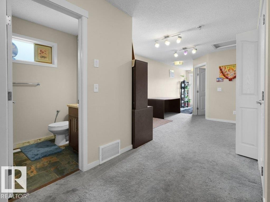 Central hallway with light-toned walls and grey carpeting - 1419 27 Av, Edmonton, AB