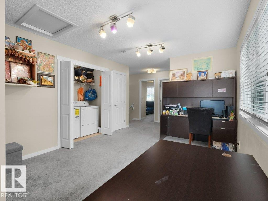 Dedicated laundry area with bi-fold doors, track lighting, ceiling fan, and carpeted flooring - 1419 27 Av, Edmonton, AB