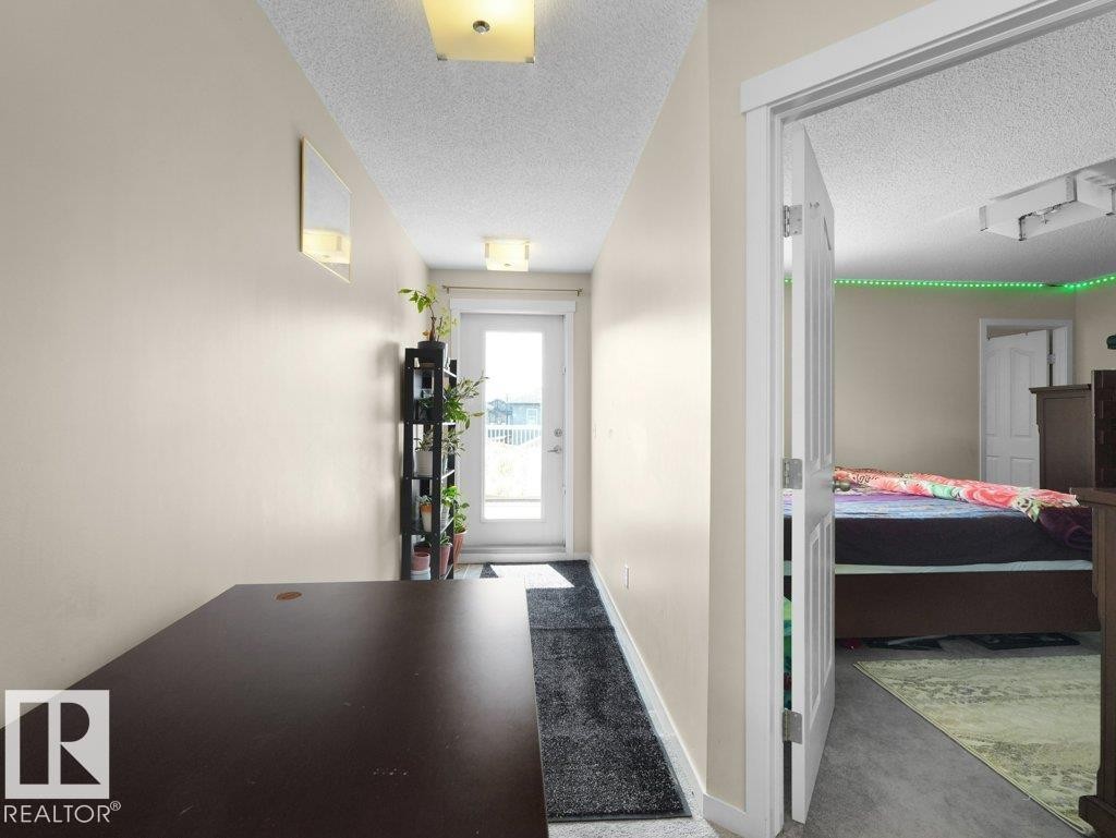 Hallway featuring neutral wall tones, overhead flush mount lighting, and a glass-paneled exterior door - 1419 27 Av, Edmonton, AB