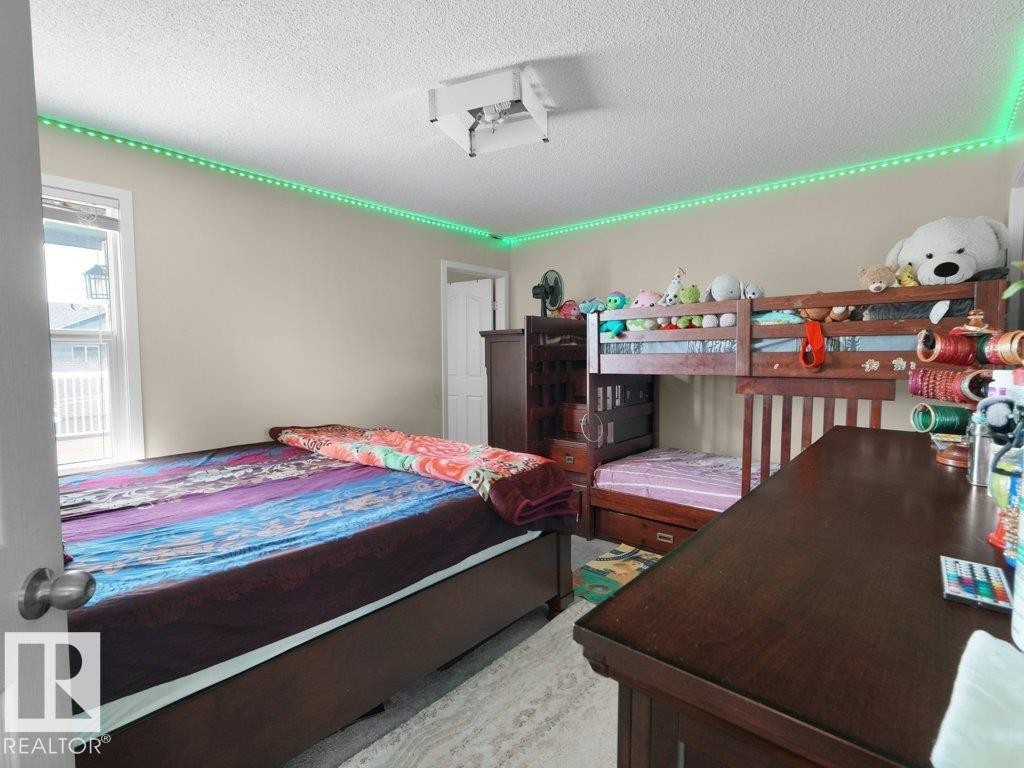 Spacious bedroom with neutral wall paint and light-colored carpeting - 1419 27 Av, Edmonton, AB