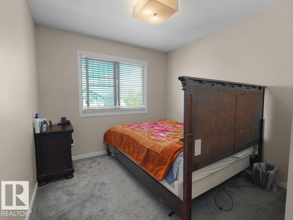 Bedroom featuring neutral wall paint, gray carpeting, a window with blinds, and a ceiling-mounted light fixture - 1419 27 Av, Edmonton, AB