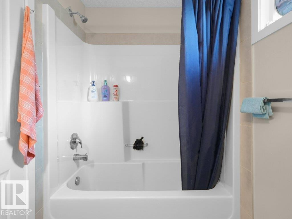 Shower-bathtub combination with bright white surround and integrated shelving - 1419 27 Av, Edmonton, AB
