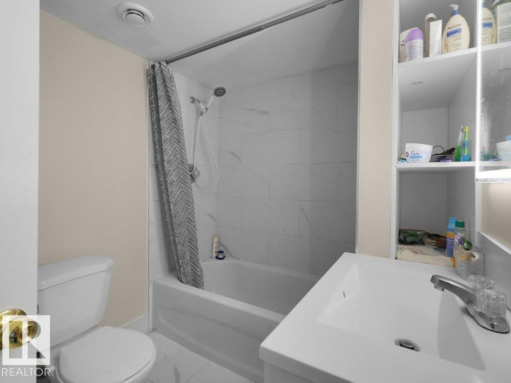 Bathroom featuring a full-size tub and shower combination with white tiled surround - 1419 27 Av, Edmonton, AB