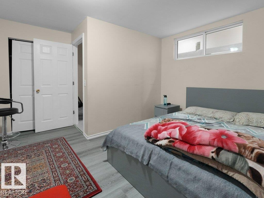 Bedroom featuring light-toned walls, wood-finish flooring, and white trim - 1419 27 Av, Edmonton, AB