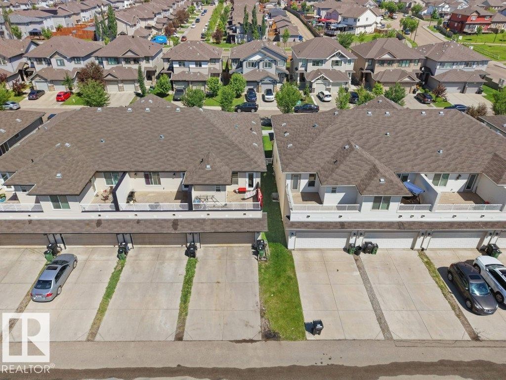 Aerial perspective showcasing townhome properties with attached garages, individual parking spaces, and second-story balconies - 1419 27 Av, Edmonton, AB