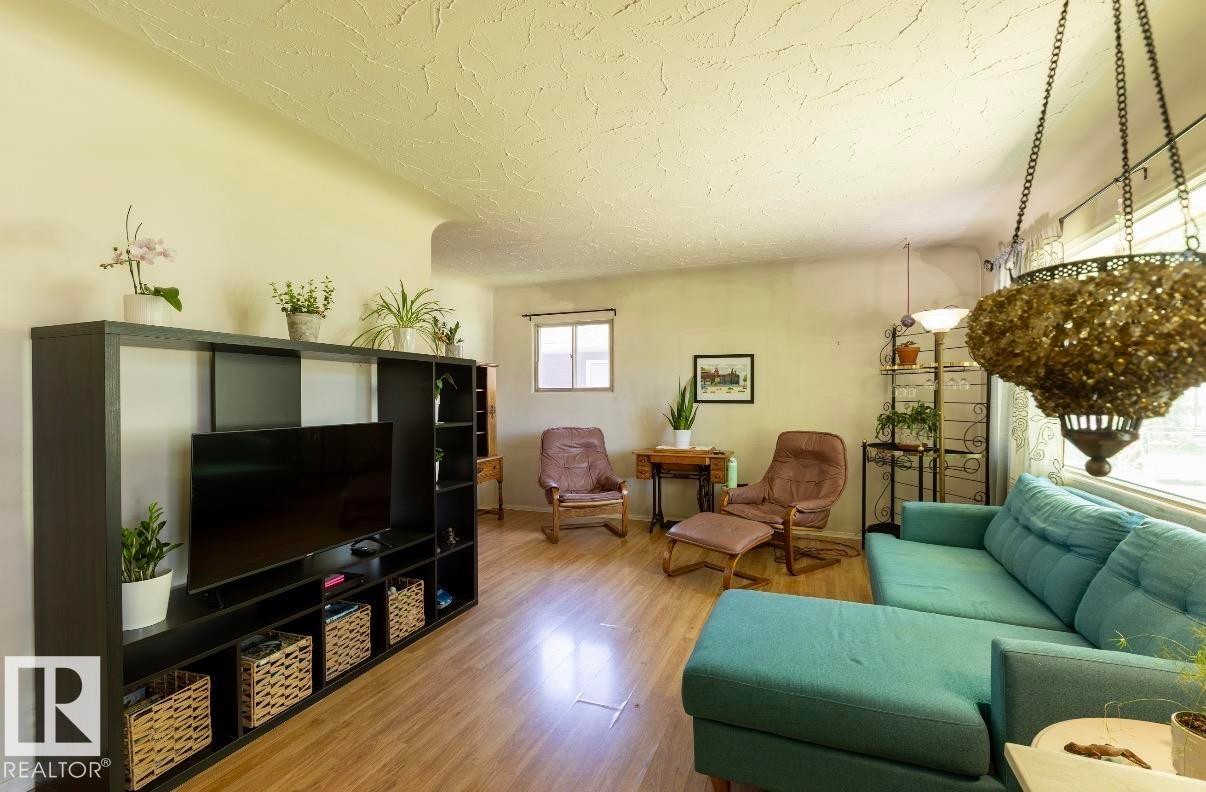 Spacious living area featuring wood-finish flooring, textured ceilings, and natural light from multiple windows - 8719 67 Avenue Nw, Edmonton, AB - Indoor Photo Showing Living Room
