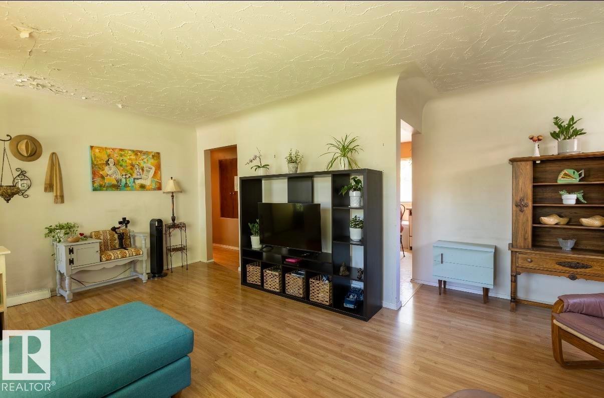 Spacious interior featuring wood-finish flooring, light-toned walls, and arched doorways - 8719 67 Avenue Nw, Edmonton, AB - Indoor Photo Showing Living Room