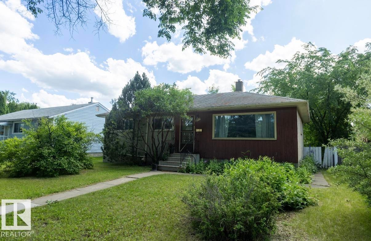 Ranch-style residence featuring a red wood-panel facade and a prominent front window - 8719 67 Avenue Nw, Edmonton, AB - Outdoor