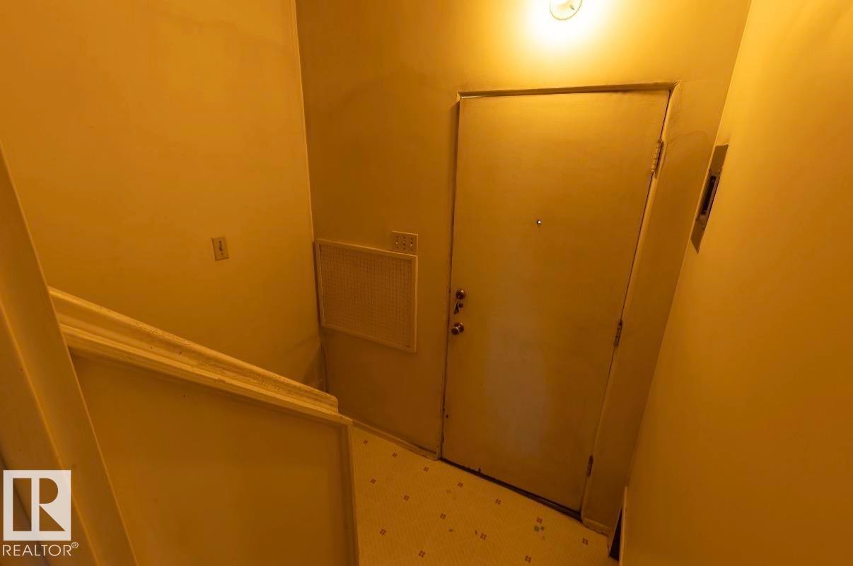Entry door with multiple locks, ceiling-mounted light fixture, and white floor tiling - 8719 67 Avenue Nw, Edmonton, AB - Indoor Photo Showing Other Room