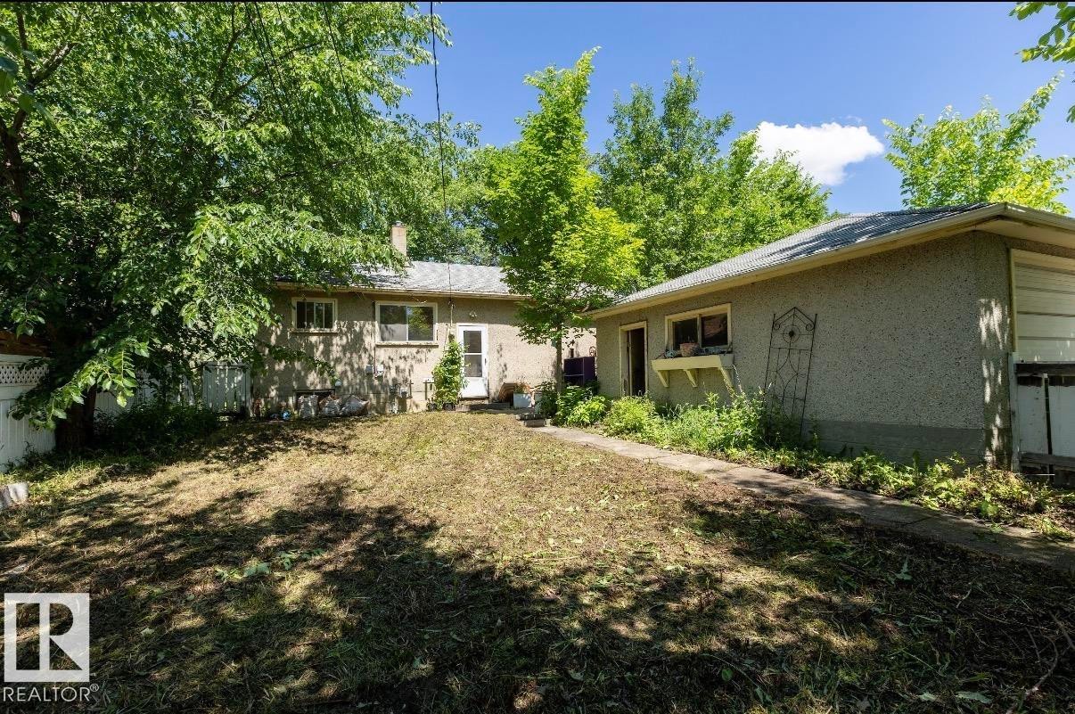 Expansive backyard featuring mature trees, a detached auxiliary building, and a concrete pathway - 8719 67 Avenue Nw, Edmonton, AB - Outdoor