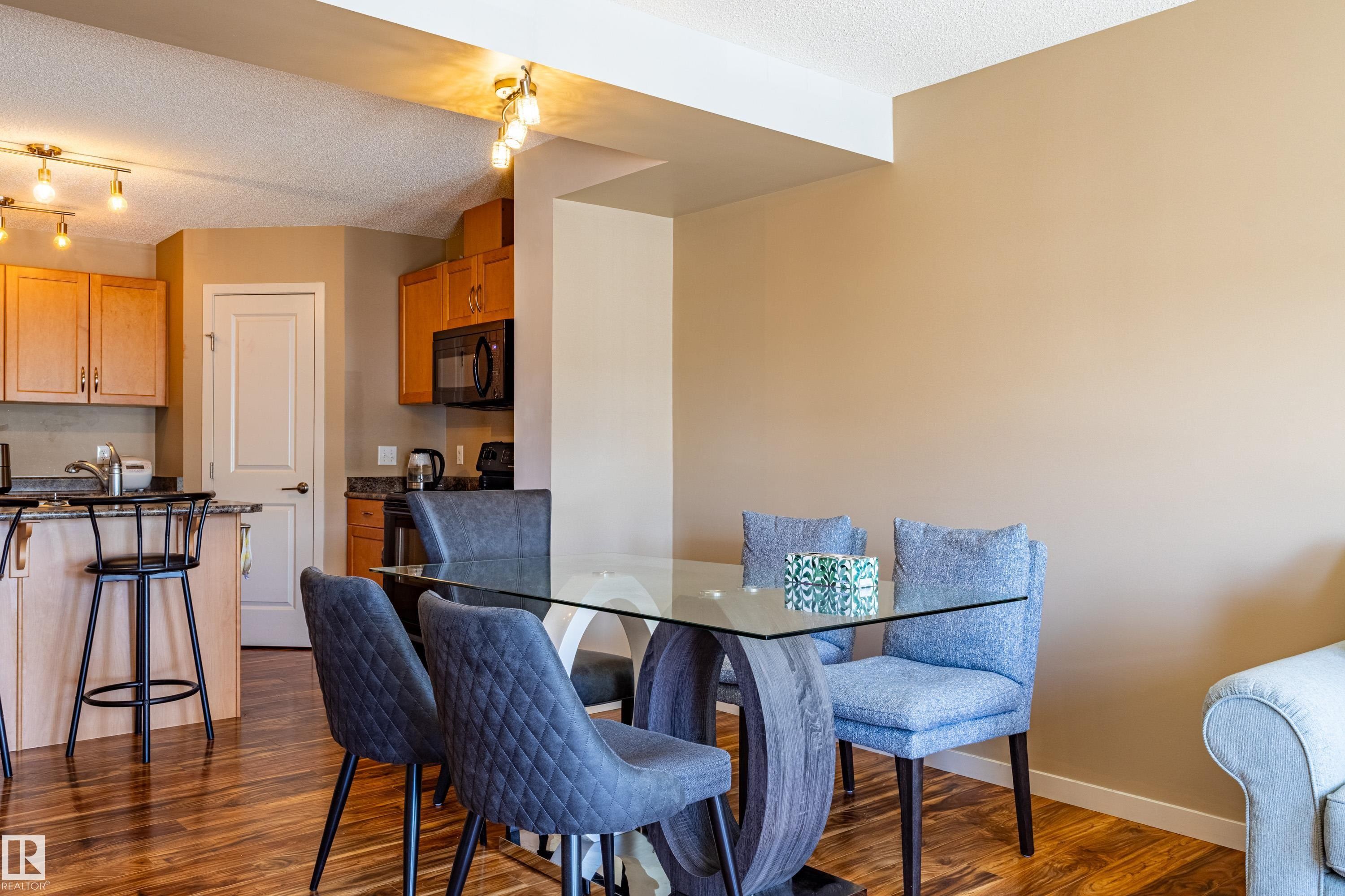 Spacious dining area with wood-finish flooring, featuring a glass-top table - 13 1816 Rutherford Road, Edmonton, AB