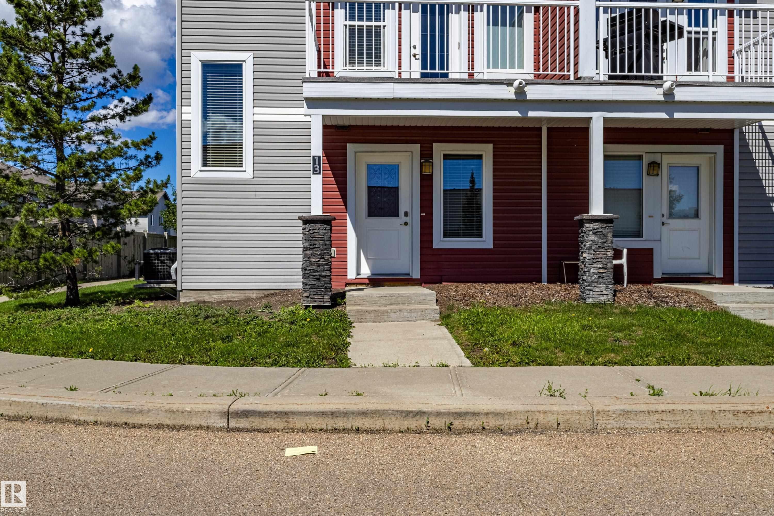 Duplex exterior featuring red and gray horizontal siding, white trim, and a second-story balcony with white railings - 13 1816 Rutherford Road, Edmonton, AB