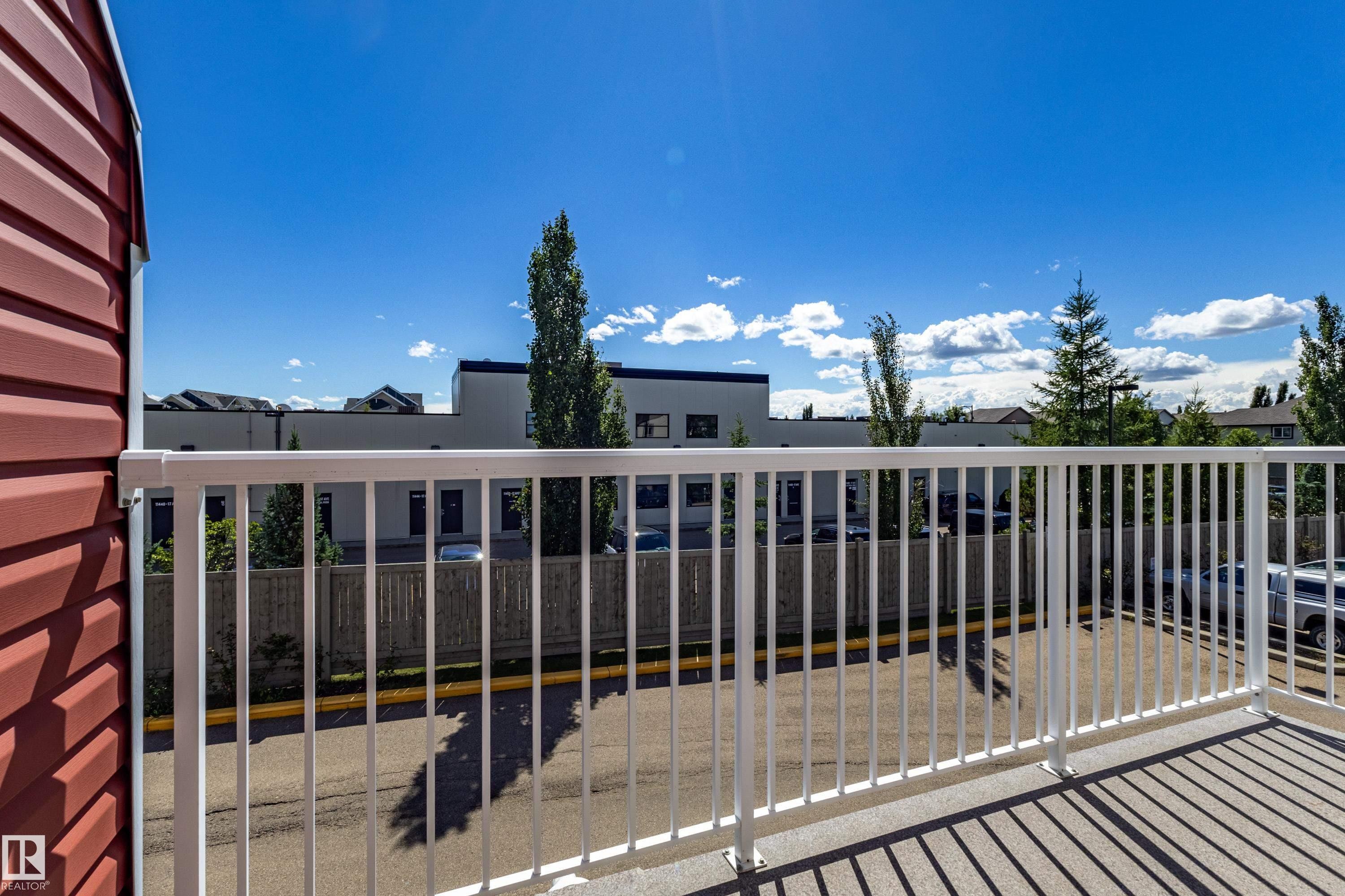 Private exterior balcony with white railing and red siding - 13 1816 Rutherford Road, Edmonton, AB