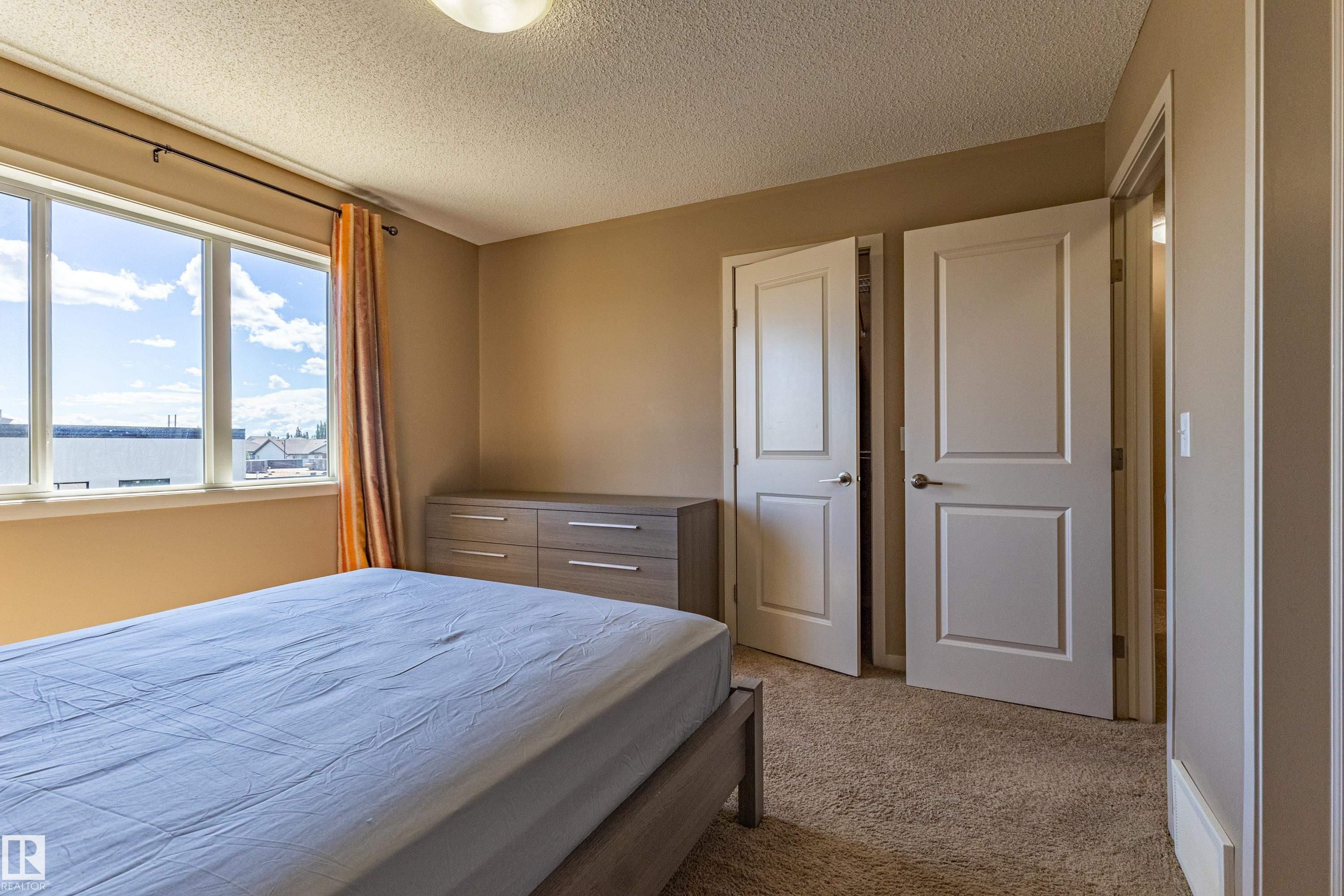 Bedroom featuring a multi-pane window, neutral-toned walls, and carpet flooring - 13 1816 Rutherford Road, Edmonton, AB