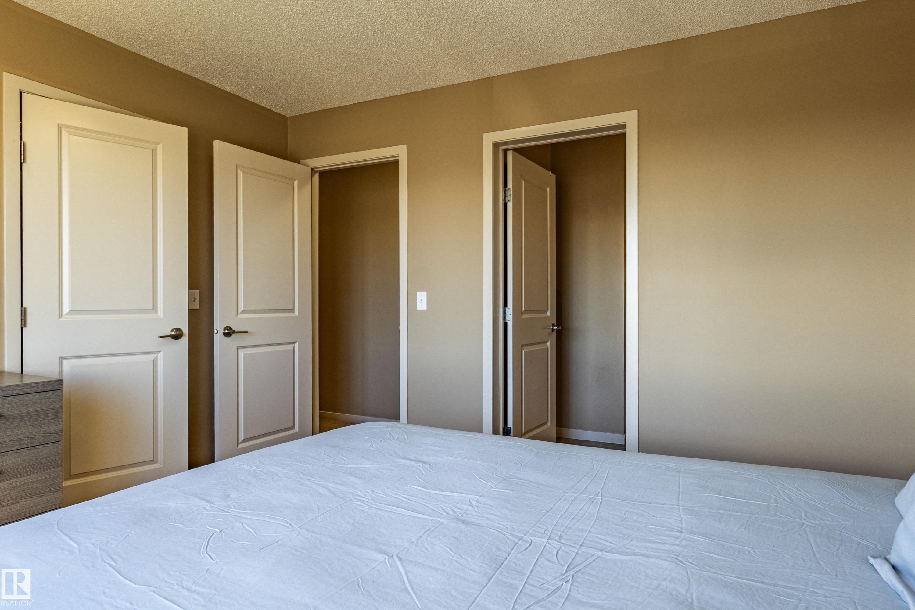 Interior space featuring two panel doors with dark hardware, a third open doorway, and neutral painted walls - 13 1816 Rutherford Road, Edmonton, AB