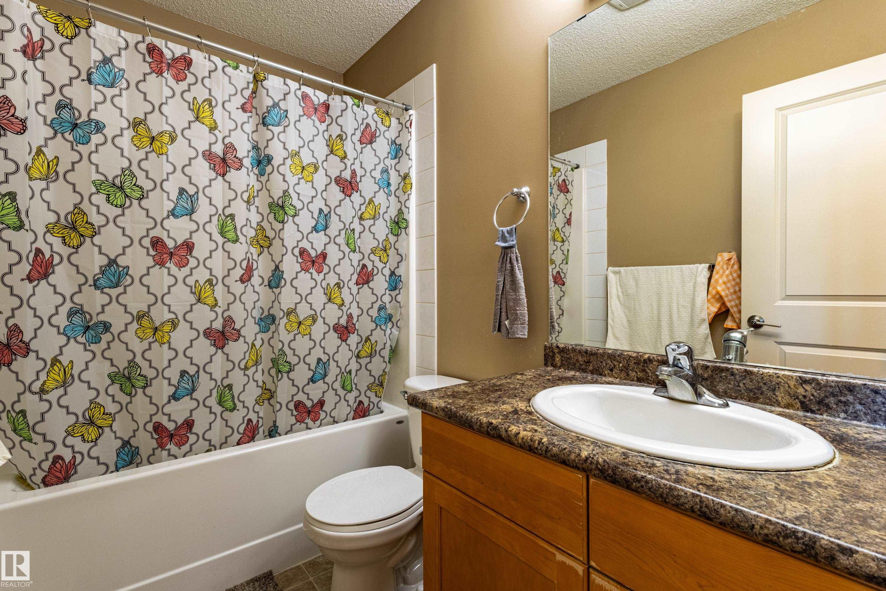 Bathroom featuring an integrated vanity sink with a laminate countertop, a shower-over-tub combination, and tiled flooring - 13 1816 Rutherford Road, Edmonton, AB