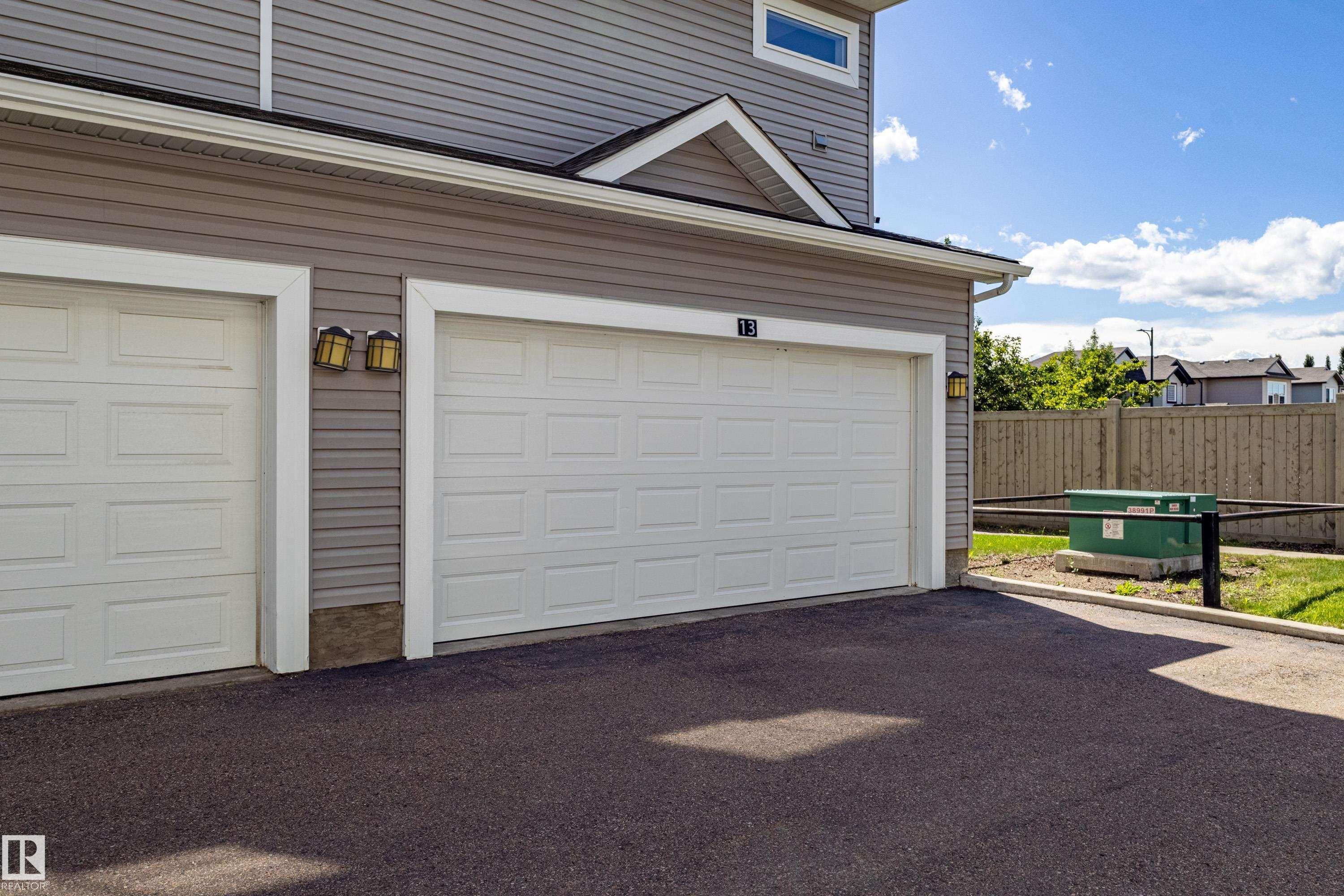 Two-car garage with panel-style doors and exterior lighting fixtures - 13 1816 Rutherford Road, Edmonton, AB