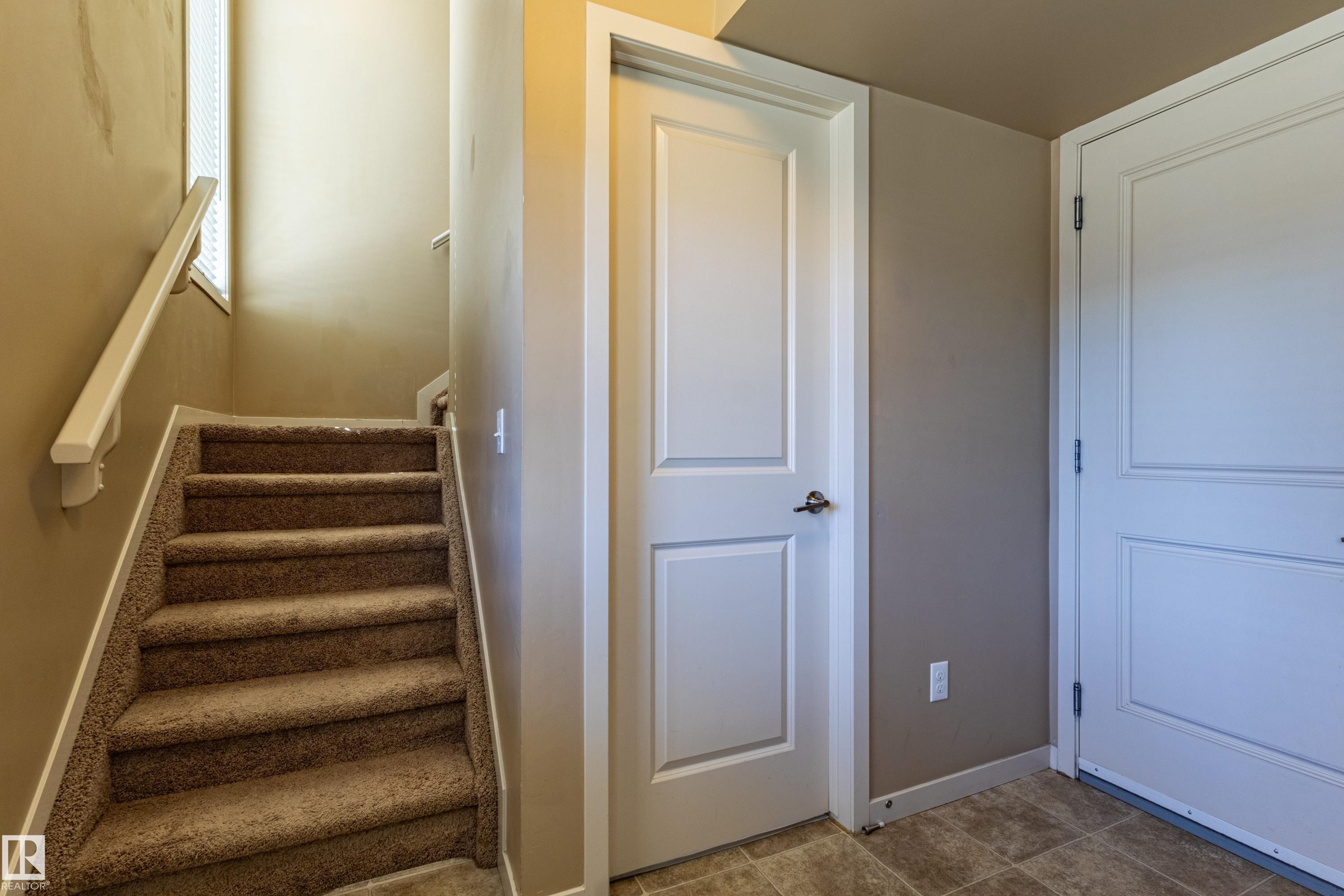 Carpeted staircase with white handrail and window feature - 13 1816 Rutherford Road, Edmonton, AB